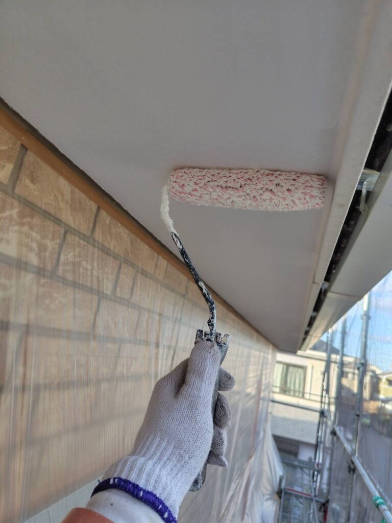 職人による軒天の塗装作業の様子。刷毛やローラーを使い、丁寧に塗料を塗布している。