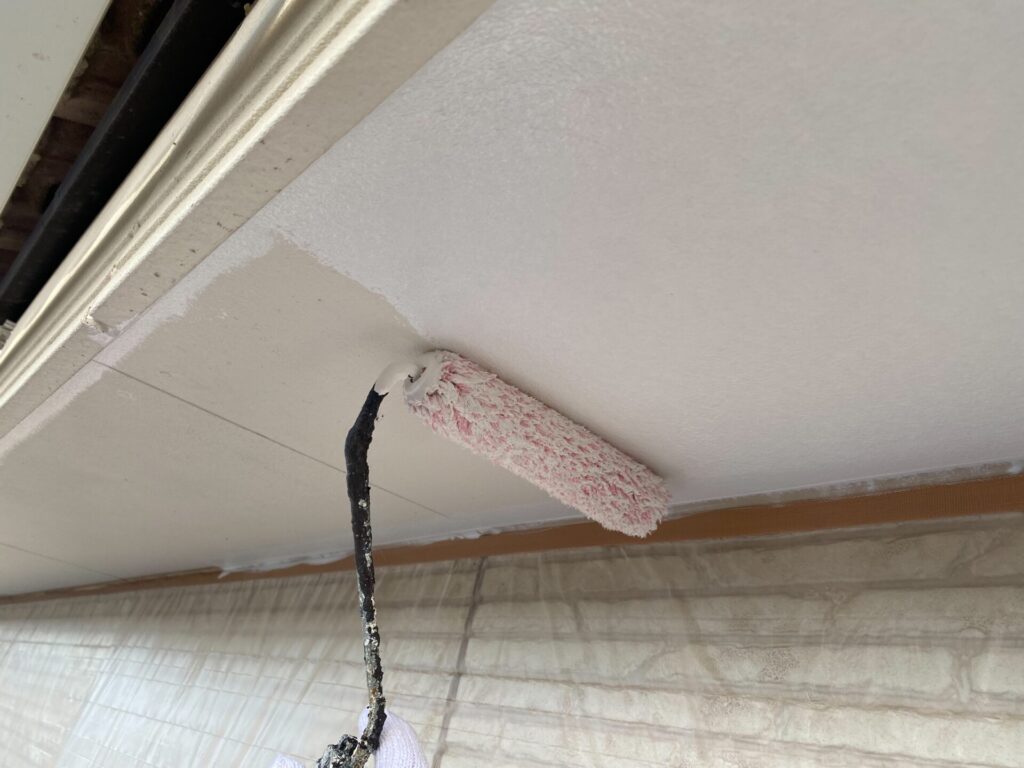 職人による軒天の塗装作業の様子。刷毛やローラーを使い、丁寧に塗料を塗布している。