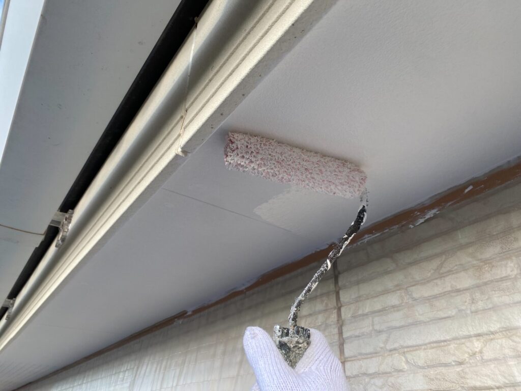 職人による軒天の塗装作業の様子。刷毛やローラーを使い、丁寧に塗料を塗布している。