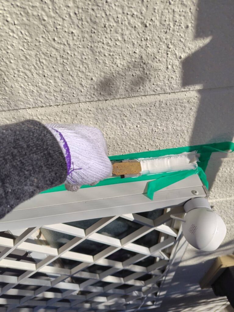 サッシ上部の狭い隙間に充填されたコーキング材をヘラで隙間なく押し込み整える作業。