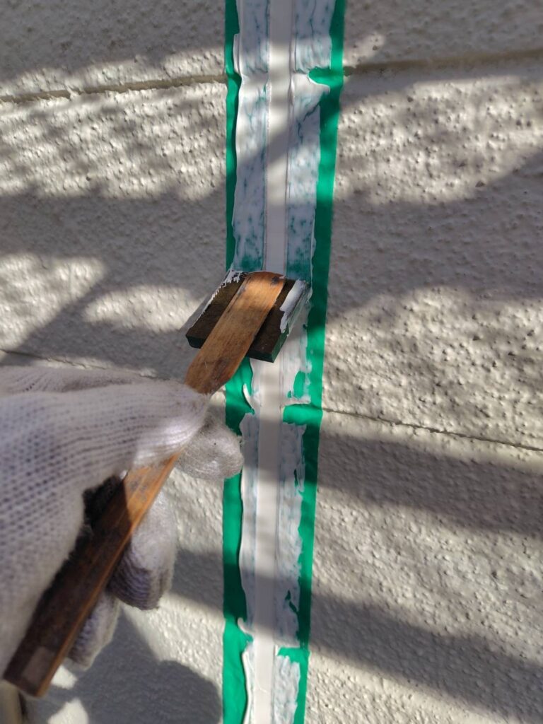 注入したばかりのコーキング材を、ヘラを使って表面を平滑に整え、圧着させている様子。