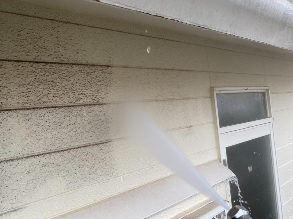 外壁塗装前の高圧洗浄：サイディングに蓄積した黒ずみや排気ガス汚れを強力な水圧で洗い流す様子