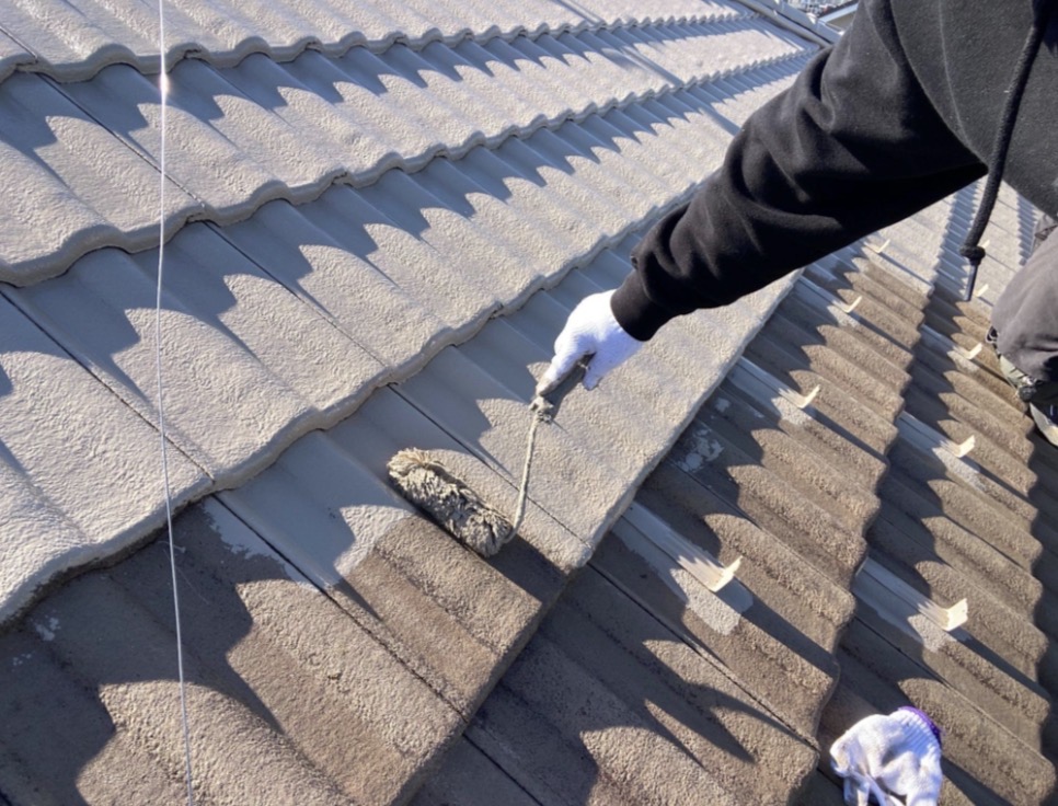 足場の上で、普段は見えない屋根の細かい隙間まで丁寧に塗装している様子