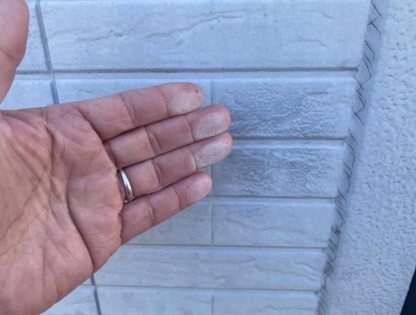 外壁塗装の劣化による白亜化（チョーキング）現象を手で確認している様子