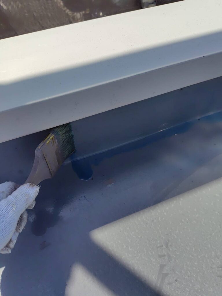 床面や立ち上がり部分の隙間に、防水材の密着性を極限まで高めるための専用下塗り材(プライマー)を均一に塗布していく様子。