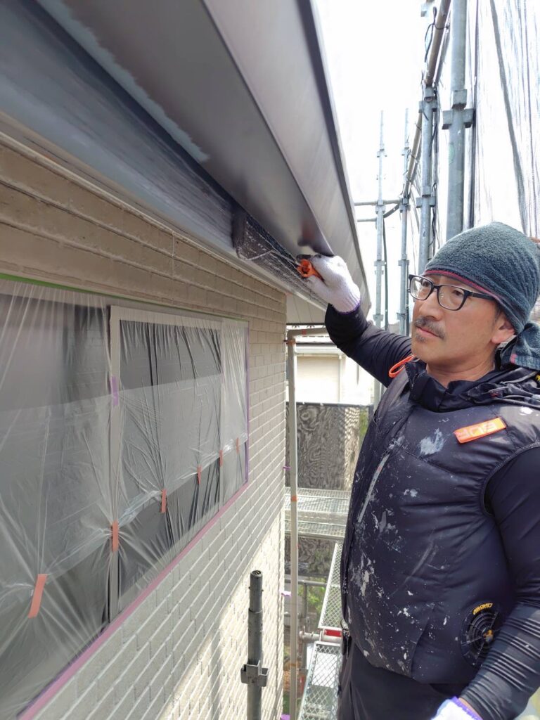 鼻隠し表面へローラーを滑らせ中塗り塗料を均一に塗布する作業風景