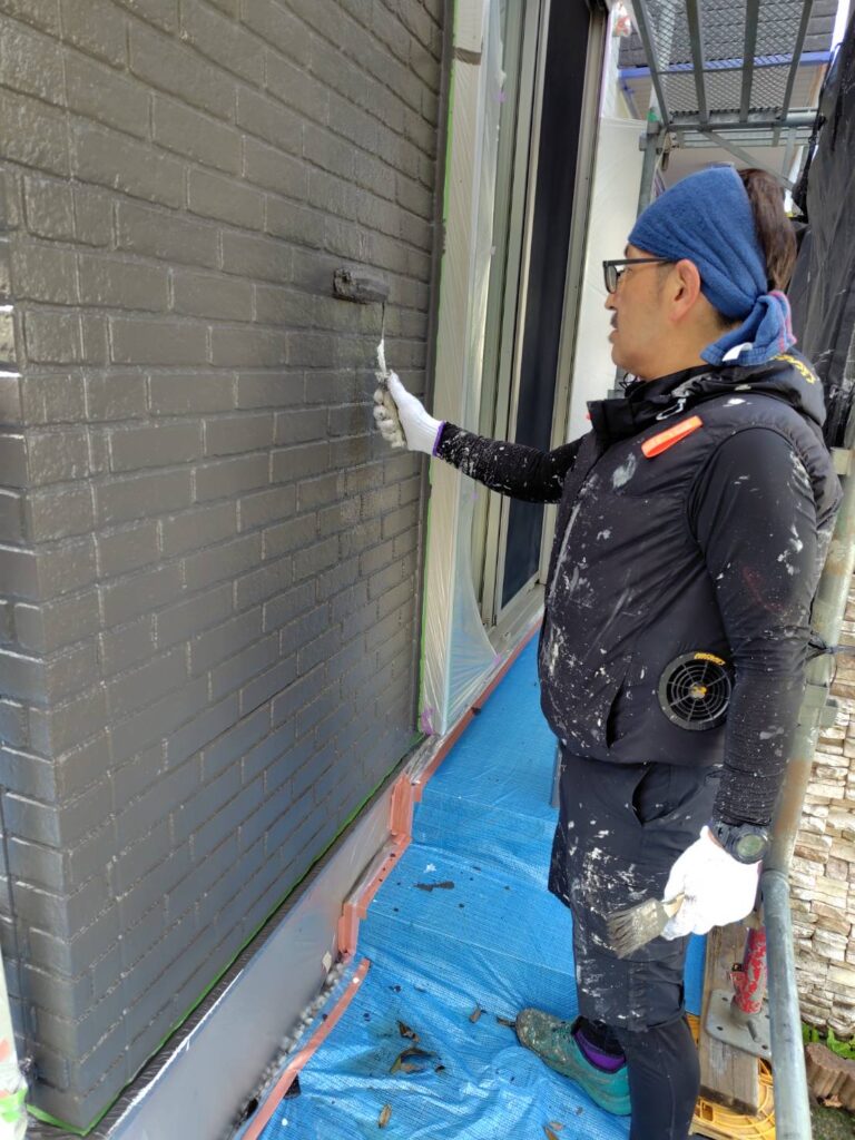 外壁デザイン部分の最終仕上げとして上塗り塗料を丁寧に塗り重ねる様子