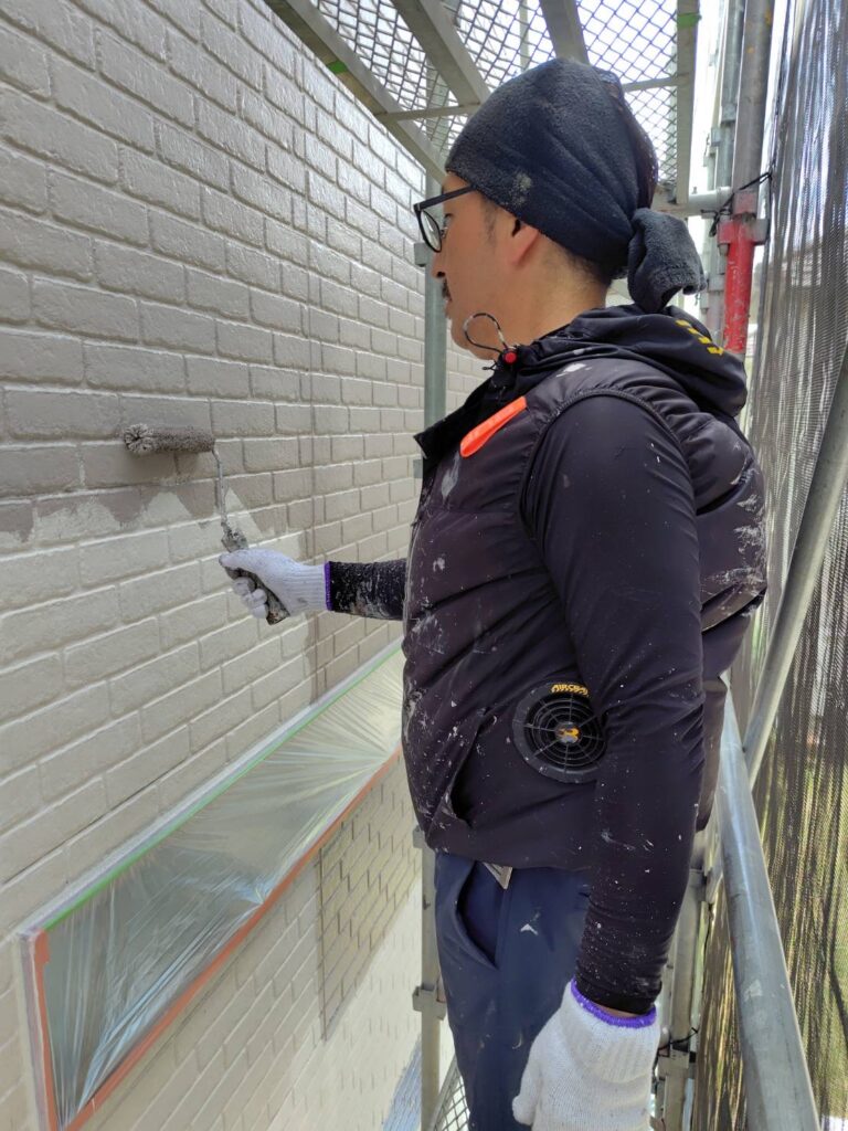 外壁ベース部分の壁面に中塗り塗料を塗布していく施工様子