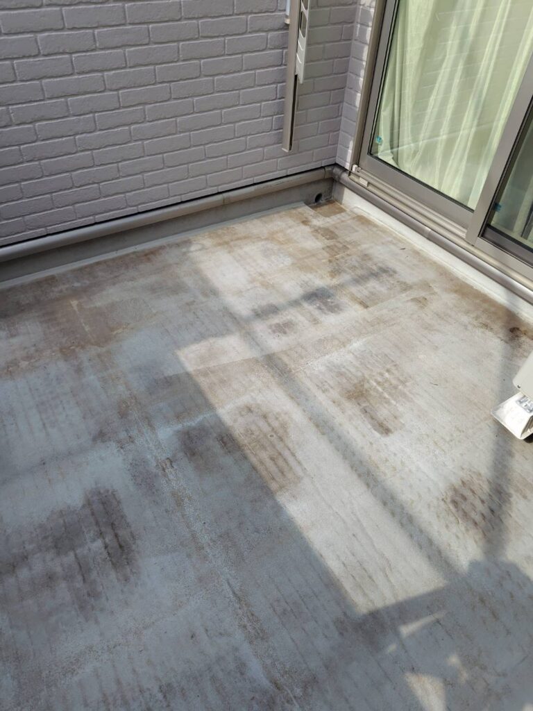 ベランダ施工前の状態。表面塗膜の擦れや黒ずみ汚れが確認できるベランダ床面