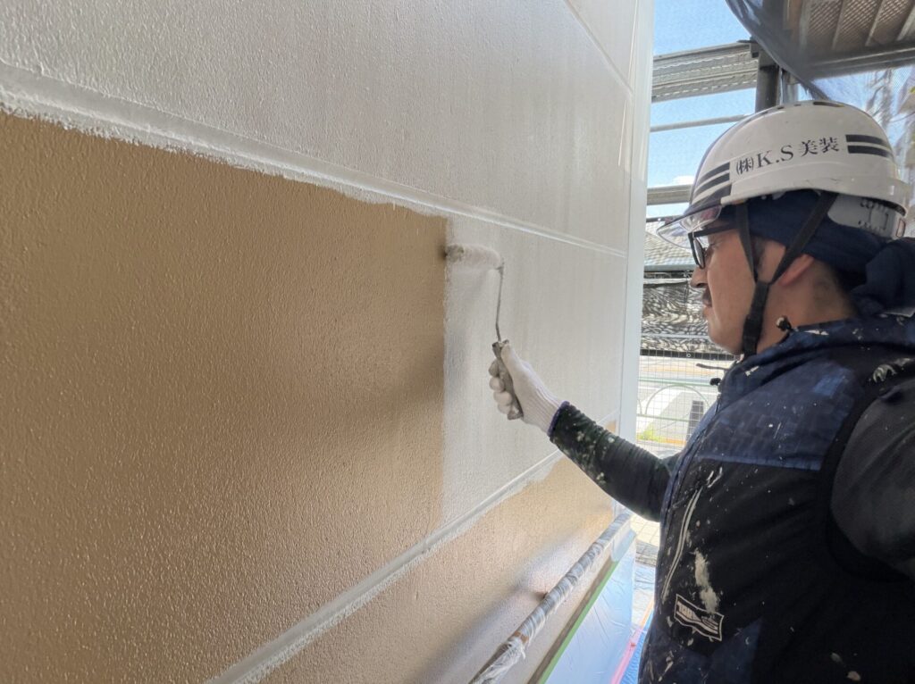 ローラーを用いて既存の外壁へ下塗り材を均一に塗布する手元