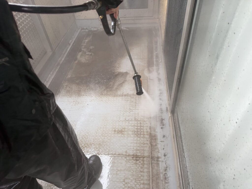 ベランダ床の蓄積汚れを高圧洗浄機で一気に洗い落とす作業